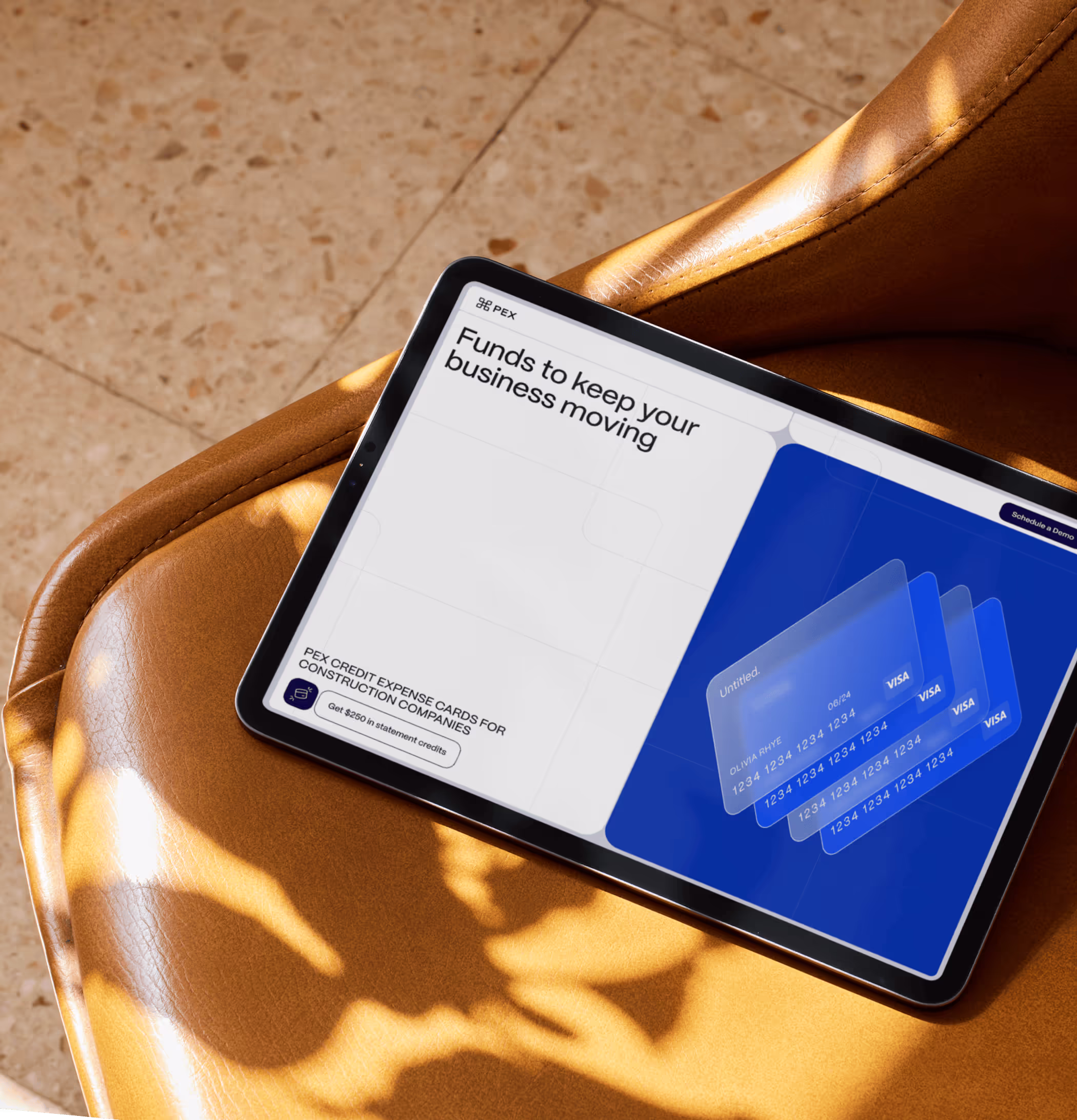 Tablet on a tan leather chair showing the PEX website: ‘Funds to keep your business moving’ with stacked Visa expense cards